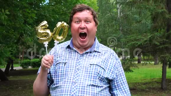 大个子拿着金色气球把50号放在户外50周年庆祝晚会视频的预览图