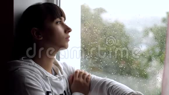 家中靠窗的沮丧年轻女子视频的预览图