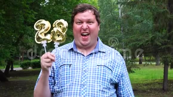 大个子拿着金色气球把28号放在户外28周年庆祝晚会视频的预览图