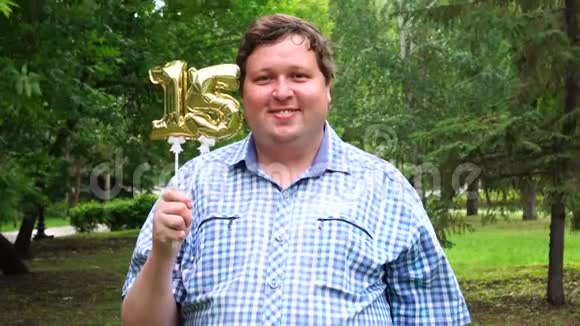 大个子拿着金色的气球把15号放在户外16周年庆祝晚会视频的预览图