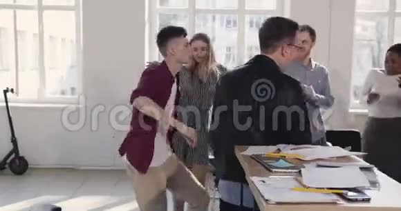 有趣的高加索公司经理做愚蠢的庆祝舞蹈与扑克脸与办公室同事一起散步视频的预览图