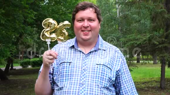 大个子拿着金色的气球把26号放在户外26周年庆祝晚会视频的预览图