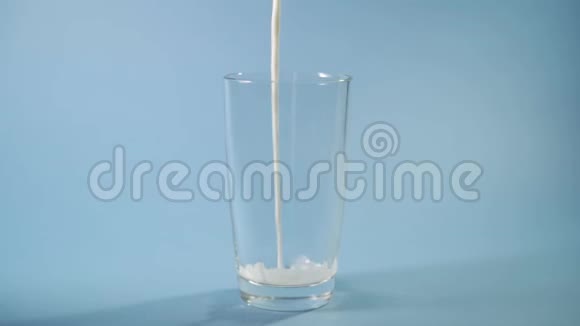 慢动作特写镜头牛奶冷饮倒入螺纹玻璃蓝色背景在工作室视频的预览图