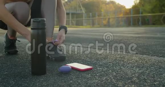 女跑步者的脚准备好用智能手表耳机和电话为音乐系鞋视频的预览图