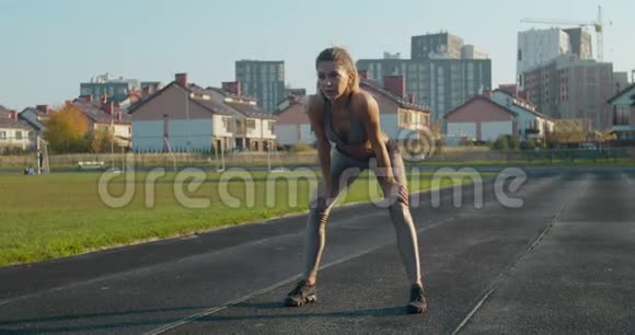 运动的金发女人完成跑步和弯腰以捕捉她的呼吸视频的预览图