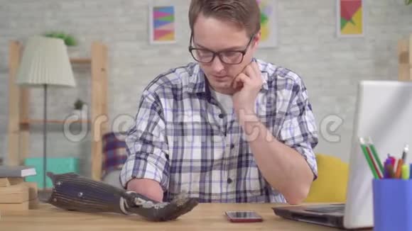坐在桌子旁的年轻人通过智能手机调节假肢视频的预览图