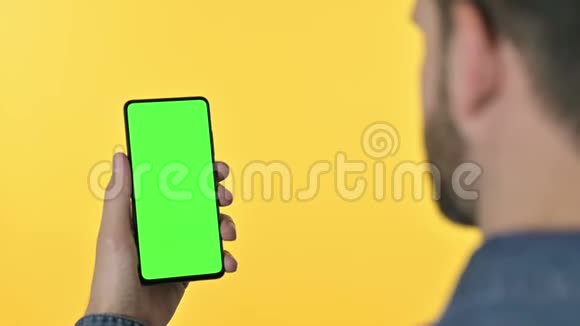带有彩色屏幕的人滚动智能手机黄色背景视频的预览图