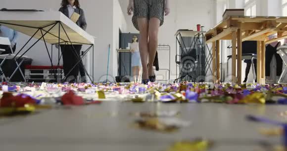 在现代办公场所美丽的女领导在五彩纸屑覆盖的地板上散步的低角度腿视频的预览图