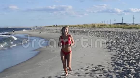 穿红色泳衣的漂亮女人在沙滩上慢动作奔跑视频的预览图