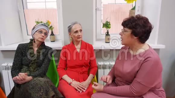 老年妇女坐在退休者俱乐部的朋友聚会上交谈视频的预览图