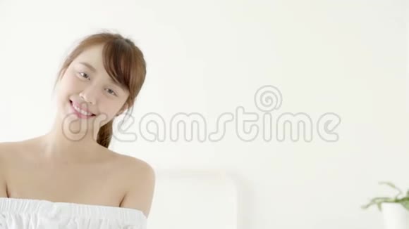美丽的肖像年轻的亚洲女人坐在床上微笑着快乐地在卧室里女孩自信的姿态再见视频的预览图