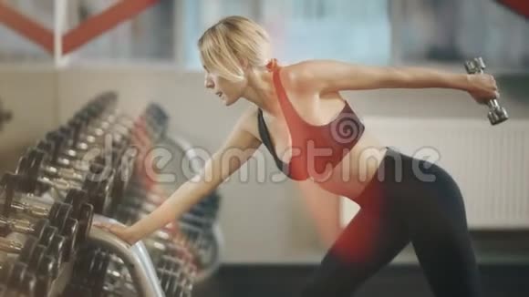 贴身女运动员在健身房用邓贝尔做手部运动视频的预览图