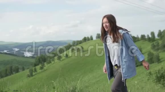 美丽的年轻女子穿过绿色的田野视频的预览图
