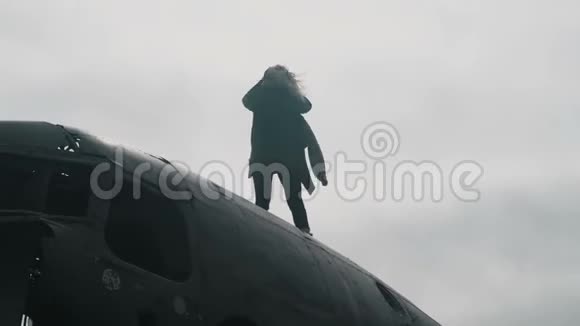 年轻的金发女人站在冰岛坠毁的DC3飞机上环顾四周头发随风飘扬视频的预览图