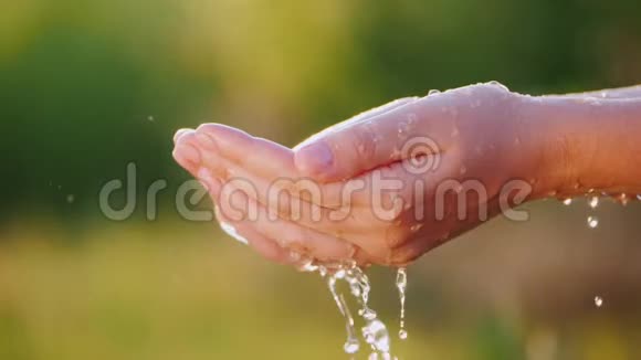双手捧着一把水水滴通过紧闭的手指流到地上节约用水概念视频的预览图