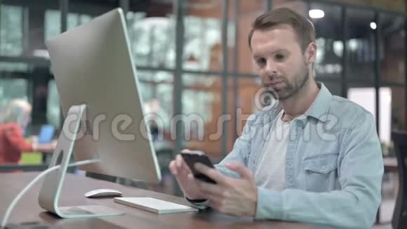 有创造力的年轻人在工作中使用智能手机和电脑视频的预览图