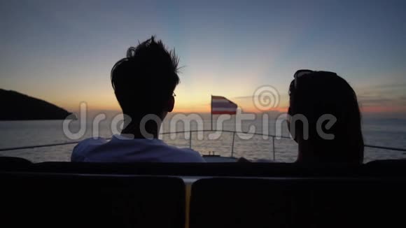 年轻人坐在游艇甲板上从后面欣赏壮丽的日落视频的预览图