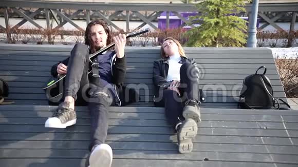 年轻夫妇躺在长凳上一个弹吉他的男人视频的预览图