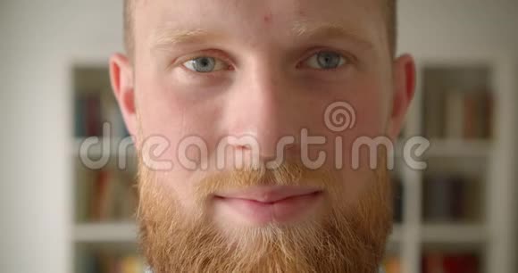 红发胡子白种人男学生的特写肖像脸上洋溢着笑容开心地看着图书馆里的摄像机视频的预览图
