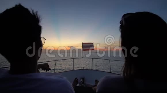两个人坐在露天的游船甲板上欣赏晚风和壮丽的日落视频的预览图