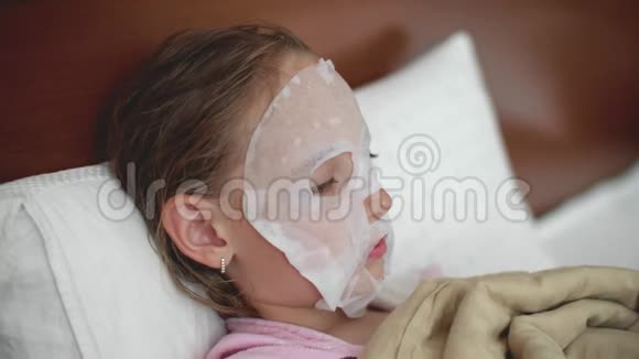 青春期前的女孩用布保湿面膜敷脸躺在床上视频的预览图