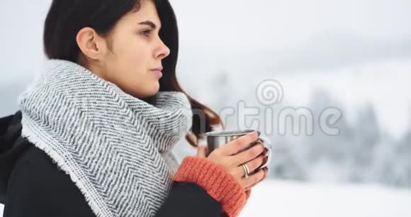 冰冻的女人在山中央喝热茶在寒冷的日子里年轻的女人喝热茶视频的预览图