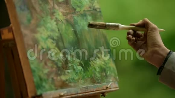 一个女孩的手掌特写一个艺术家用画笔在她的画上做模糊的触摸视频的预览图