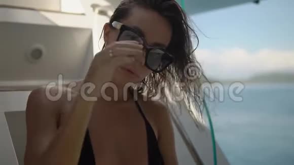 一个年轻漂亮的模特戴着黑色时尚太阳镜在海船上摆姿势慢动作用一根头发固定视频的预览图