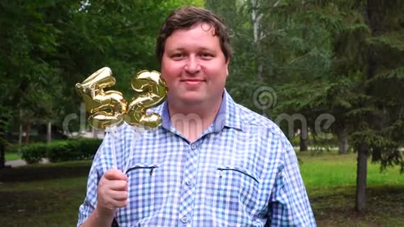 大个子拿着金色气球把52号放在户外52周年庆祝晚会视频的预览图