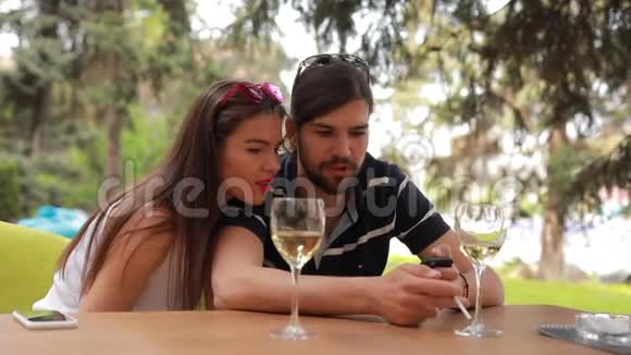 夫妻约会男人和女人坐在桌子旁看着智能手机上的东西视频的预览图