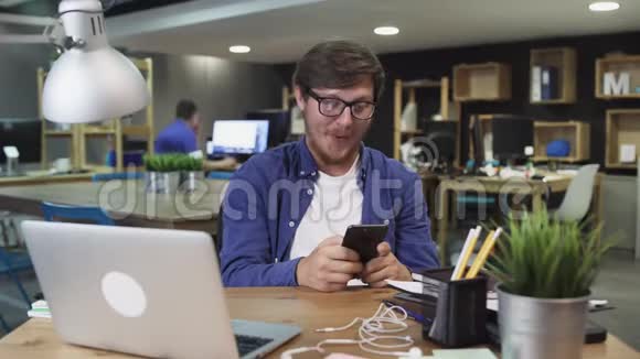 快乐的年轻人在办公室里使用智能手机通过互联网手表视频和使用社交视频的预览图