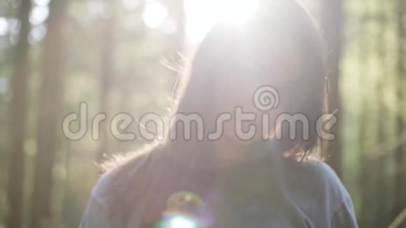 美丽的女人在绿色的森林里站在阳光下望着远方的肖像那个女孩在森林里徒步旅行视频的预览图