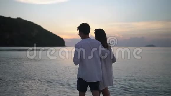 年轻人晚上在海边散步年轻人一只手拿着酒杯和女友拥抱在一起视频的预览图