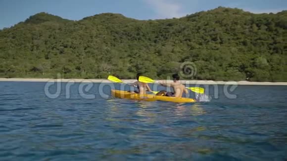 两个年轻人正积极地坐在皮艇上穿过蔚蓝的海洋海湾慢动作美妙的时光视频的预览图