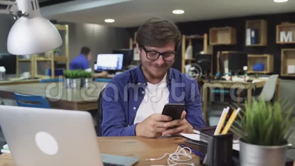 快乐的年轻人在办公室里使用智能手机通过互联网手表视频和使用社交视频的预览图