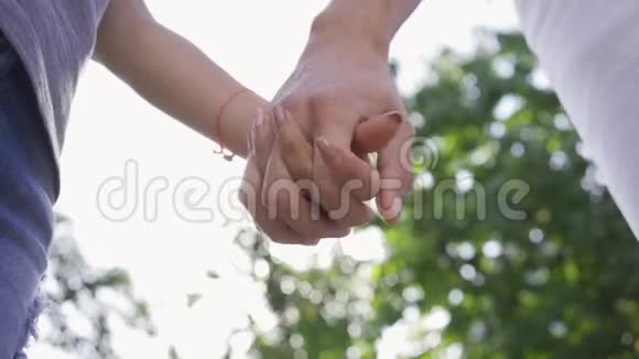 男人和女人手牵手的特写镜头温柔的关系年轻夫妇在户外消磨时间底部视图视频的预览图