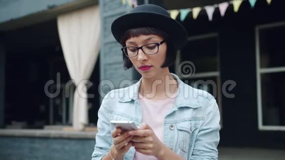 快乐的年轻女性在城市街头使用现代智能手机触摸屏幕视频的预览图