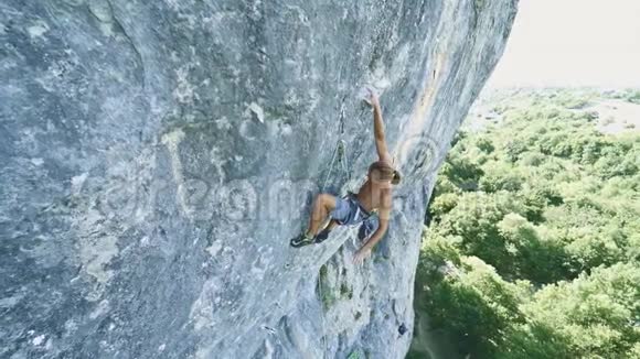 男子攀岩者挂在一根绳子上在艰难的运动路线上休息和粉笔手视频的预览图