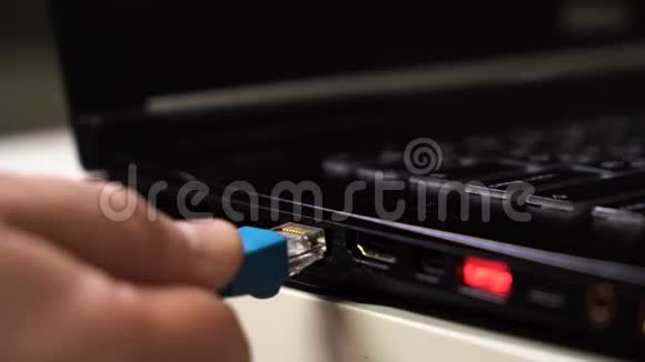 特写男性手连接蓝色以太网电缆笔记本电脑与发光的红色usb端口视频的预览图