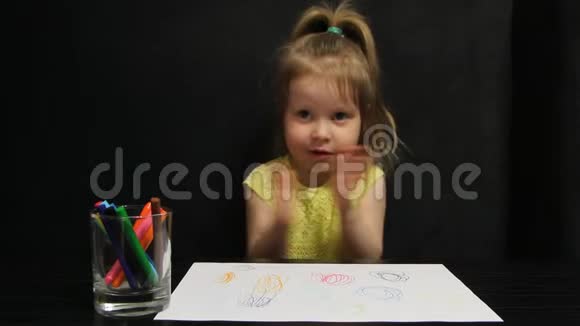小女孩一边画画一边拍着桌子一边坐在一张深灰色的沙发上一边拍着手和鬼脸视频的预览图