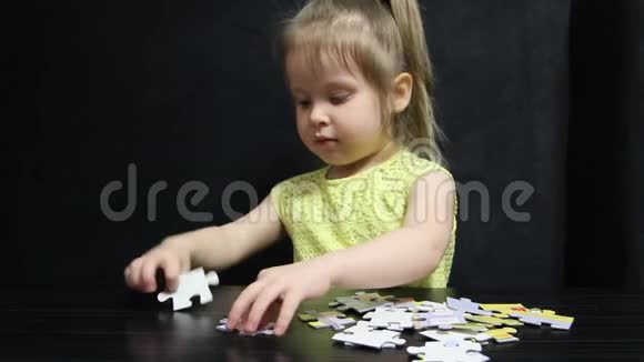 小女孩在一张深灰色背景的桌子上收集拼图视频的预览图