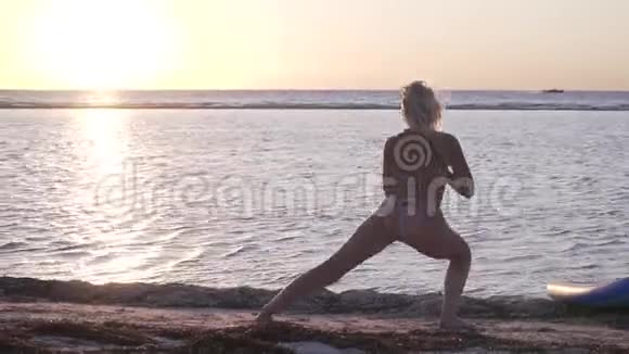穿比基尼的年轻女士正在海滩上伸展阳光明媚的地平线上视频的预览图