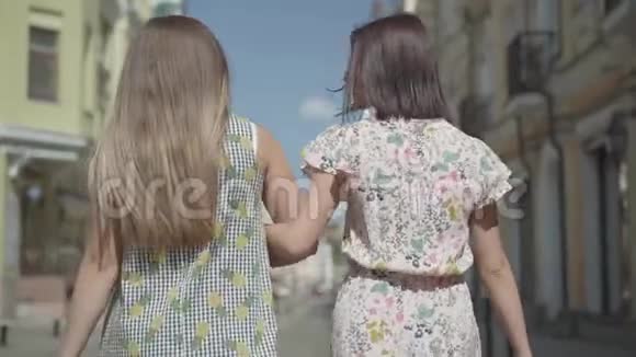 两个带购物袋的步行妇女的后景年轻女孩穿着时髦的夏装享受着花钱视频的预览图