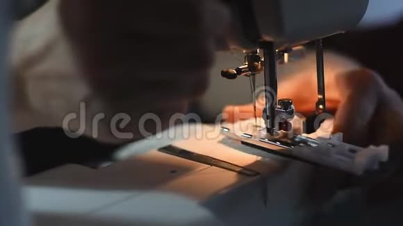 缝纫机的针形机构在内置灯的灯光下快速移动双手缝合导轨视频的预览图