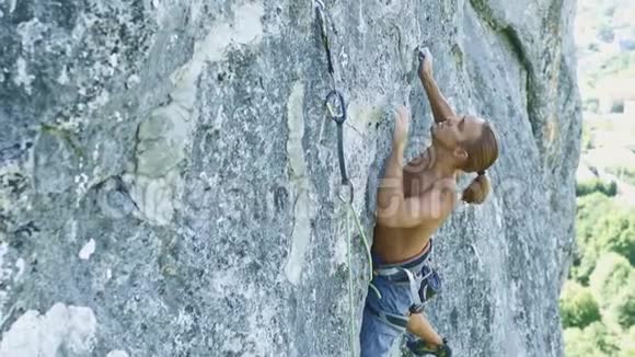 山顶风景年轻强壮肌肉黝黑的男子攀岩者攀登在高高的垂直石灰石悬崖上视频的预览图