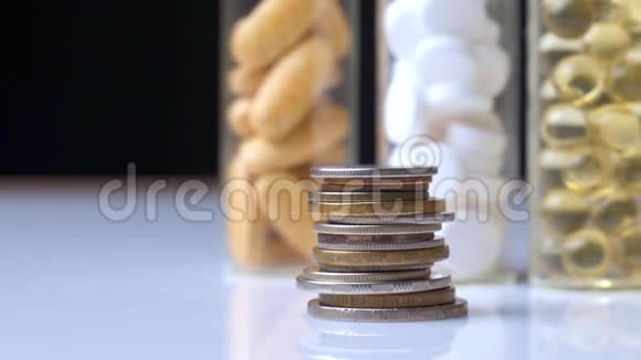 一叠硬币放在三瓶药丸的背景下视频的预览图