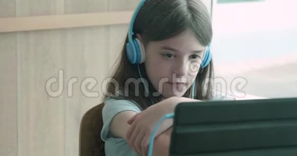 看着平板电脑的小女孩对着镜头微笑视频的预览图