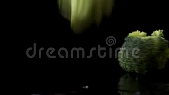 许多绿色的新鲜西兰花落在玻璃上溅起水花在黑暗的背景下缓慢地滴着水视频的预览图