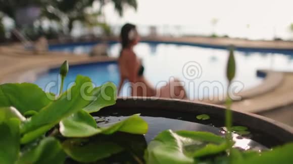 坐在热带度假游泳池旁的轻松女士视频的预览图