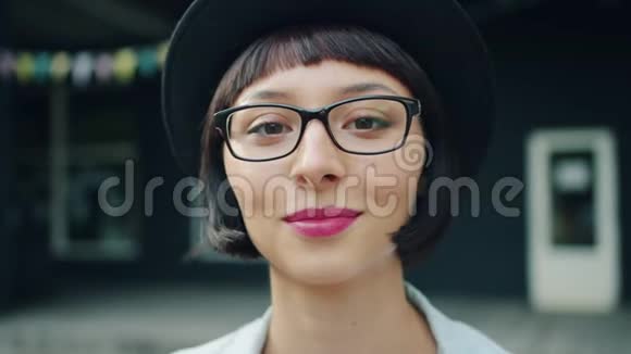 戴眼镜戴帽子在户外微笑的年轻漂亮女孩的特写照片视频的预览图